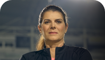 Mia Hamm standing in front of a darkened background