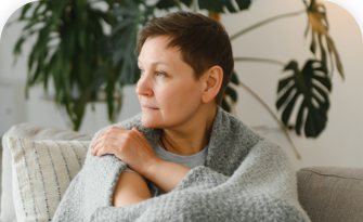woman with short hair wrapped in blanket on a couch